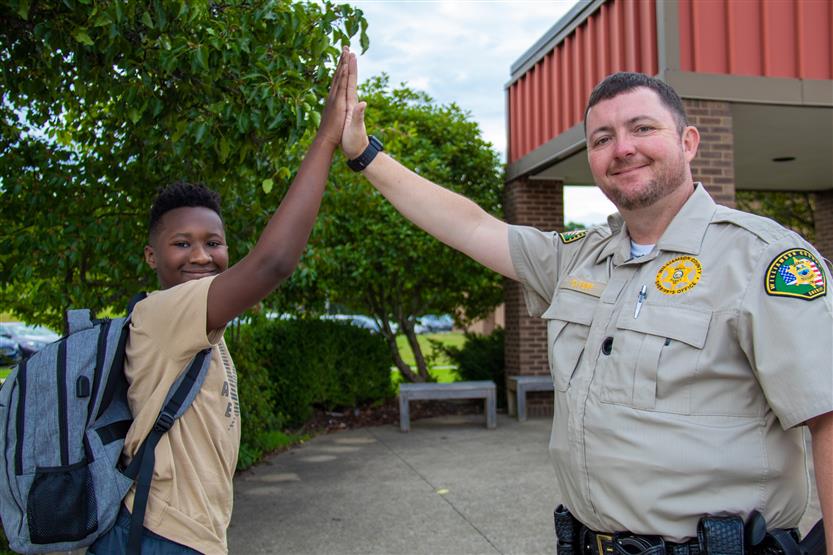 A School Resource Officer high fives a student